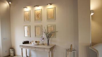 A hallway with framed botanical prints on the wall, a console table with decorative items, and a small mirror.