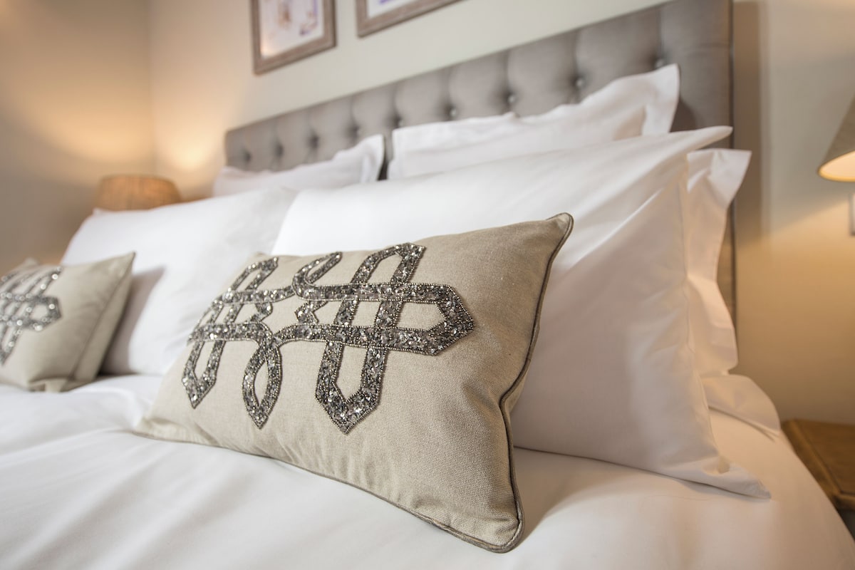Un lit avec du linge de lit blanc et des coussins décoratifs à motifs géométriques.