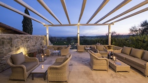 An outdoor patio with wicker furniture, stone walls, and a view of the landscape.