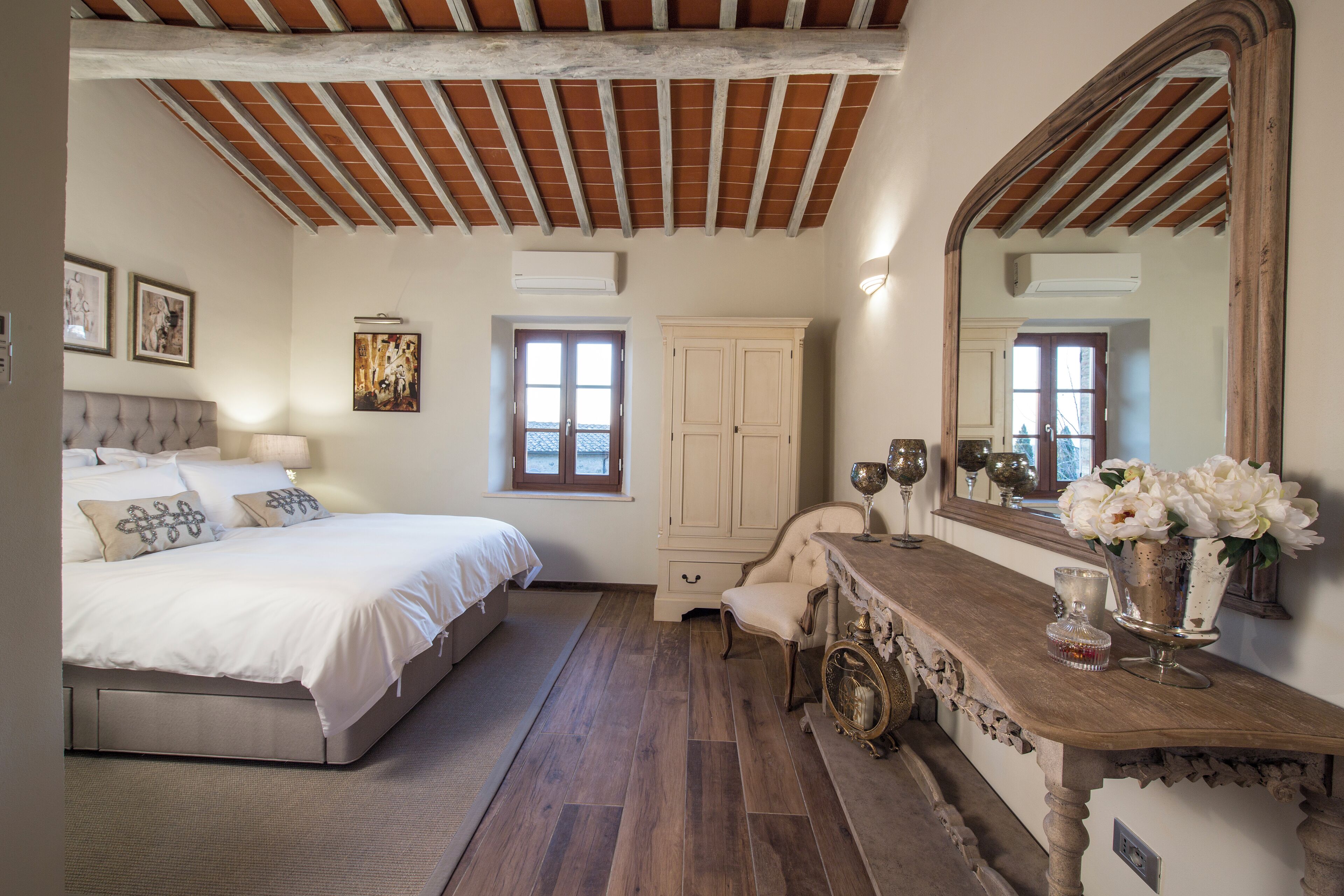 Un dormitorio con cama, tocador con espejo, cómoda y silla.