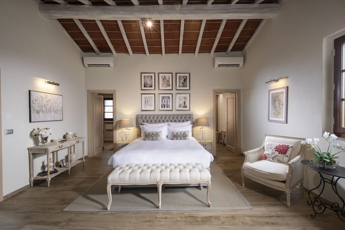Une chambre spacieuse dotée d’un grand lit, d’un coin salon et offrant une vue sur l’extérieur.