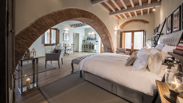 A bedroom with a large bed, a wooden ceiling, and a brick archway.