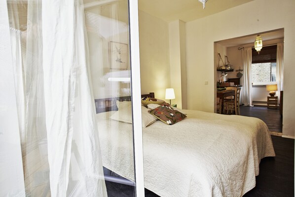 Une chambre d’hôtel avec un lit, une table de chevet, une lampe et une fenêtre avec des rideaux.