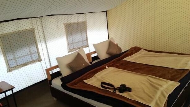 Una habitación de hotel con cama, una mesita y ventana con cortinas.