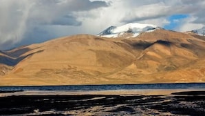 Un paisaje montañoso con un pico nevado y una masa de agua al frente.