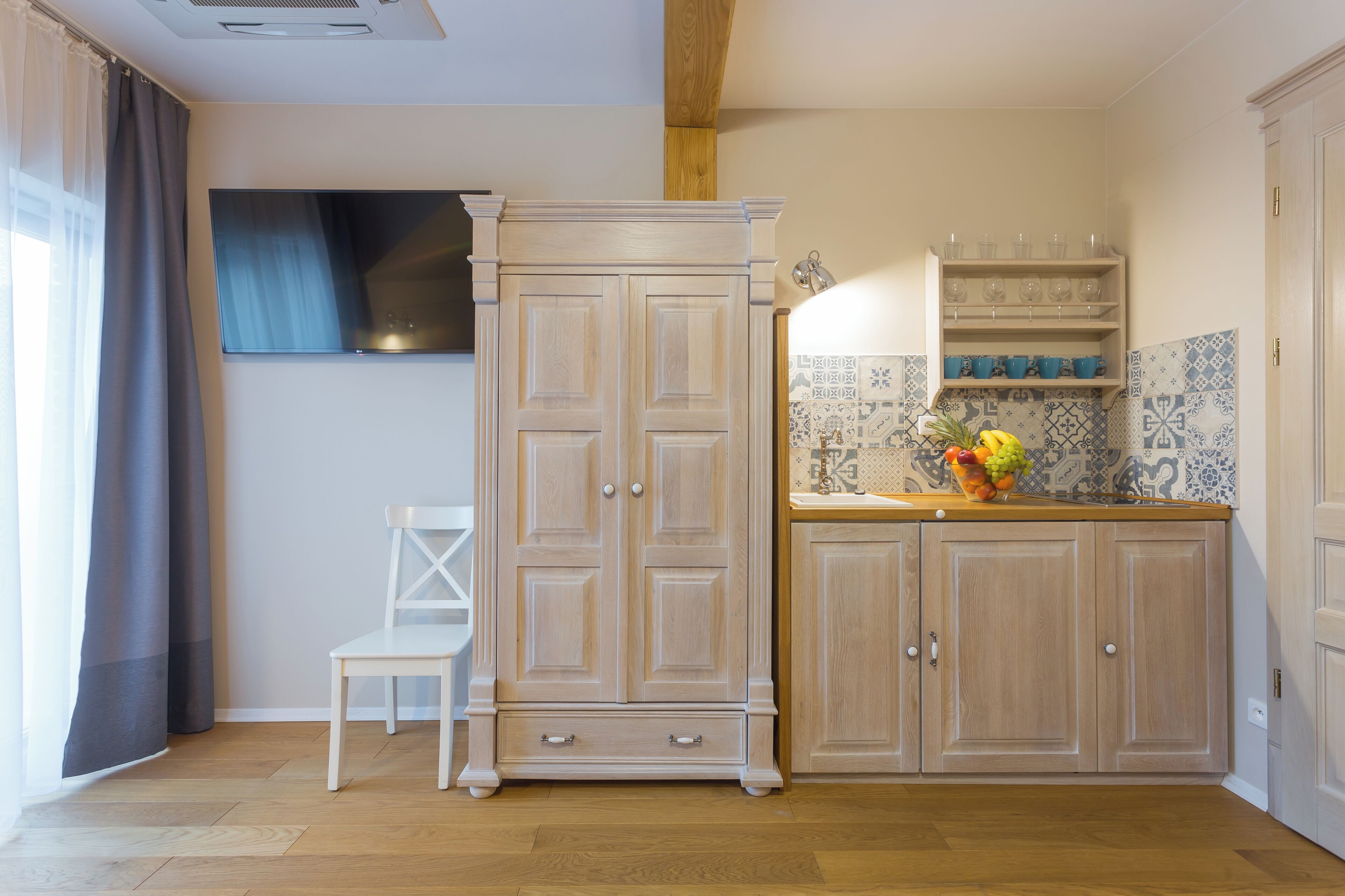 A kitchen with wooden cabinets, a white chair, and a fruit bowl on the counter.