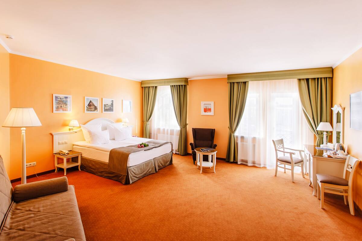 Hotellihuone, jossa on sänky, työpöytä, tuoli, lamppu ja yöpöytä.