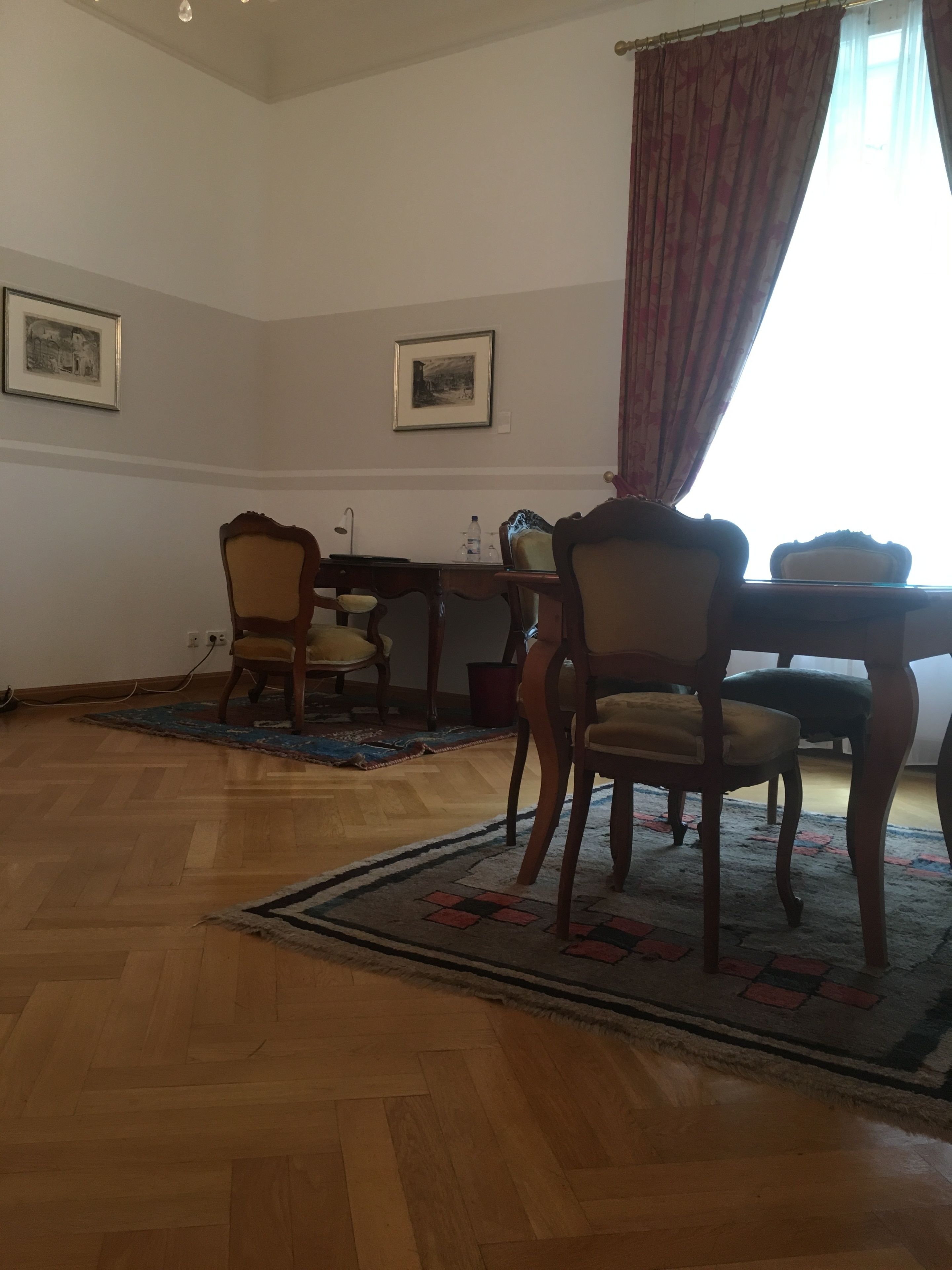 A dining area with wooden flooring, a table, chairs, and a rug.