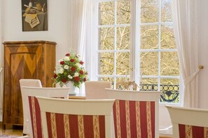 Un coin repas comprenant une table, des chaises et une fenêtre donnant sur la forêt.