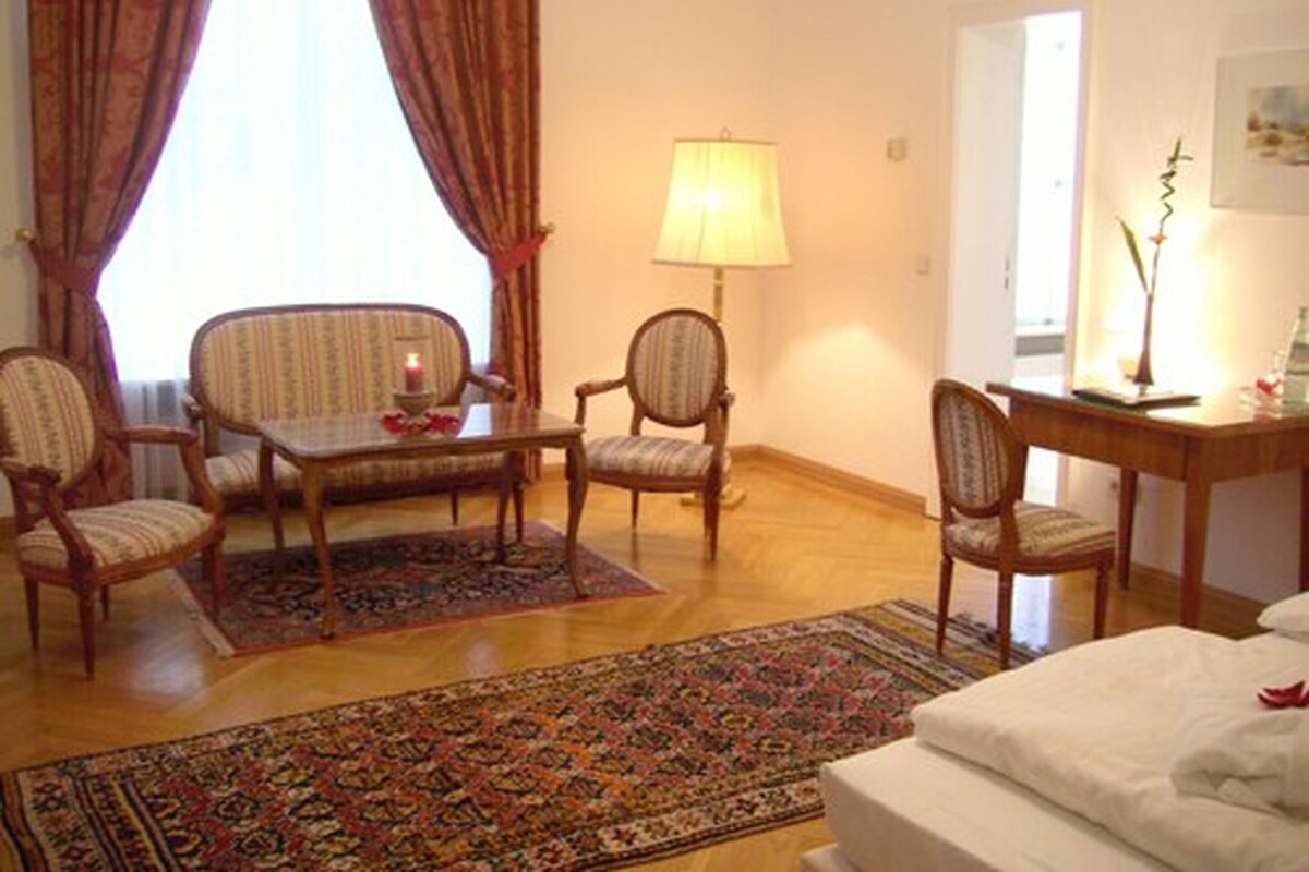 Ein Hotelzimmer mit einem Bett, zwei Sessel, einem kleinen Tisch, einer Lampe und einem Teppich.