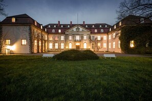 Un grand bâtiment historique à la façade symétrique, doté de nombreuses fenêtres et d’une entrée centrale.