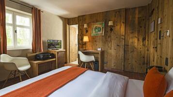 Una habitación de hotel con cama, escritorio, silla, televisor y paredes de madera.
