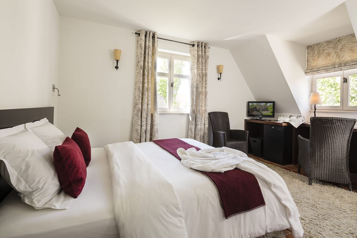 Een hotelkamer met een bed, een bureau, een televisie en een stoel.