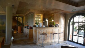Un área de bar con armarios de madera, taburetes y lámparas colgantes.