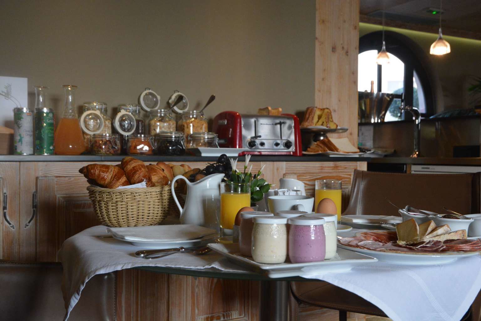 Un desayuno con croissants, huevos y diferentes condimentos sobre una mesa.