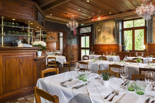 Ein Restaurant mit Holzeinrichtung, weißen Tischdecken und grünem Glaswaren.