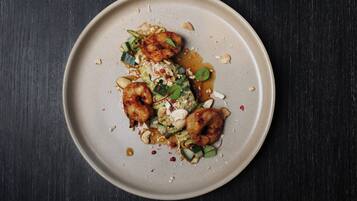 A plate of food with shrimp, vegetables, and sauce on a dark surface.