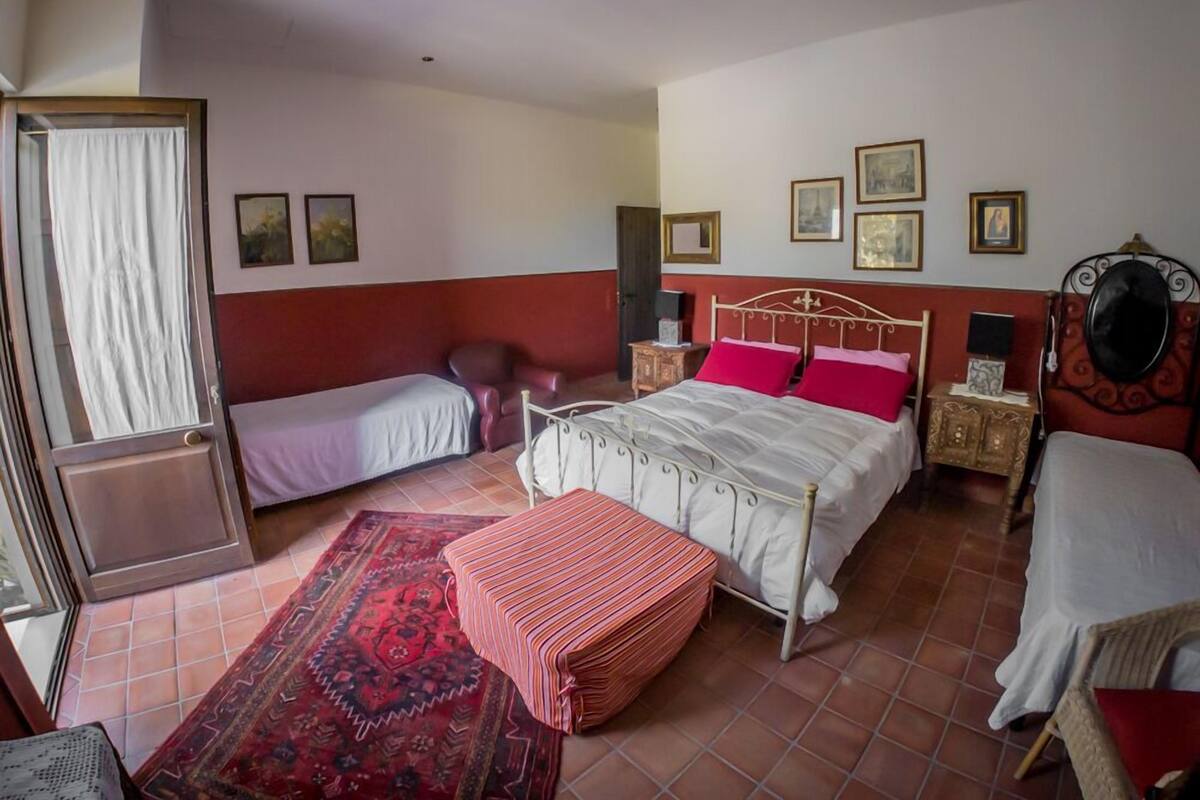 Un dormitorio con dos camas, una paleta de colores rojo y blanco, una alfombra estampada y cuadros en la pared.