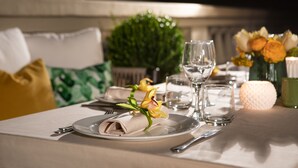 A neatly set dining table with a folded napkin, a glass, and a small vase with flowers.