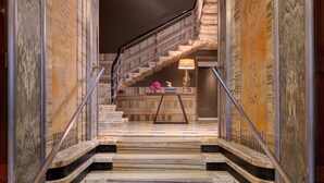 A marble staircase leading to a landing with a lamp and a decorative item. - Singer Palace Hotel Roma (Rome)