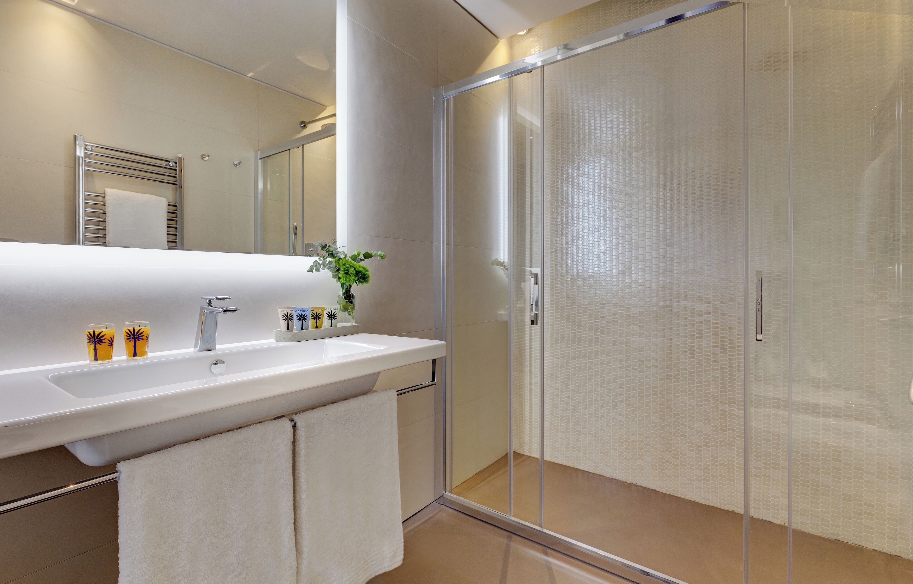 A modern bathroom with a glass shower enclosure, a white sink, and a mirror above it.
