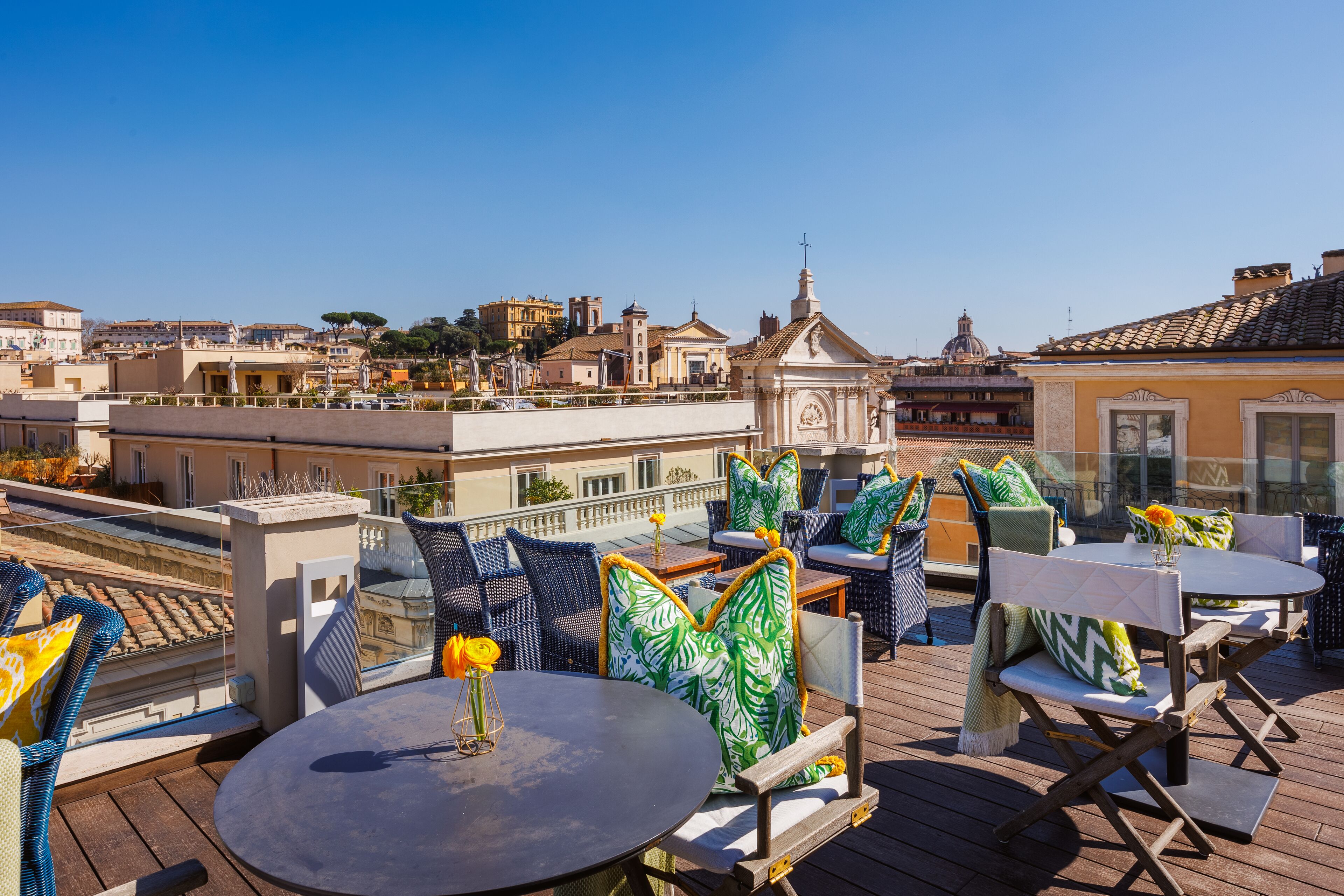 A rooftop terrace with outdoor seating, a view of the cityscape, and a small church in the background.