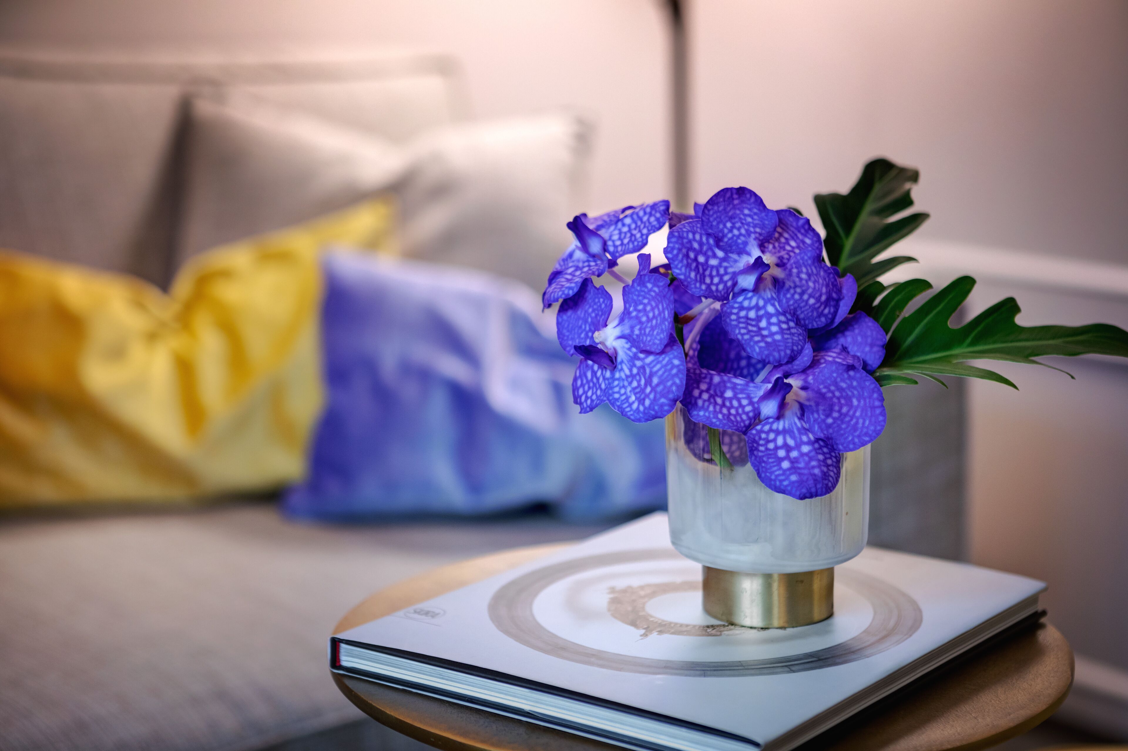 Un vaso con fiori viola su un tavolo vicino a un libro.