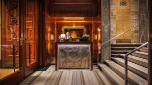 A reception area with a marble floor, a reception desk, and a staircase with a metal railing.