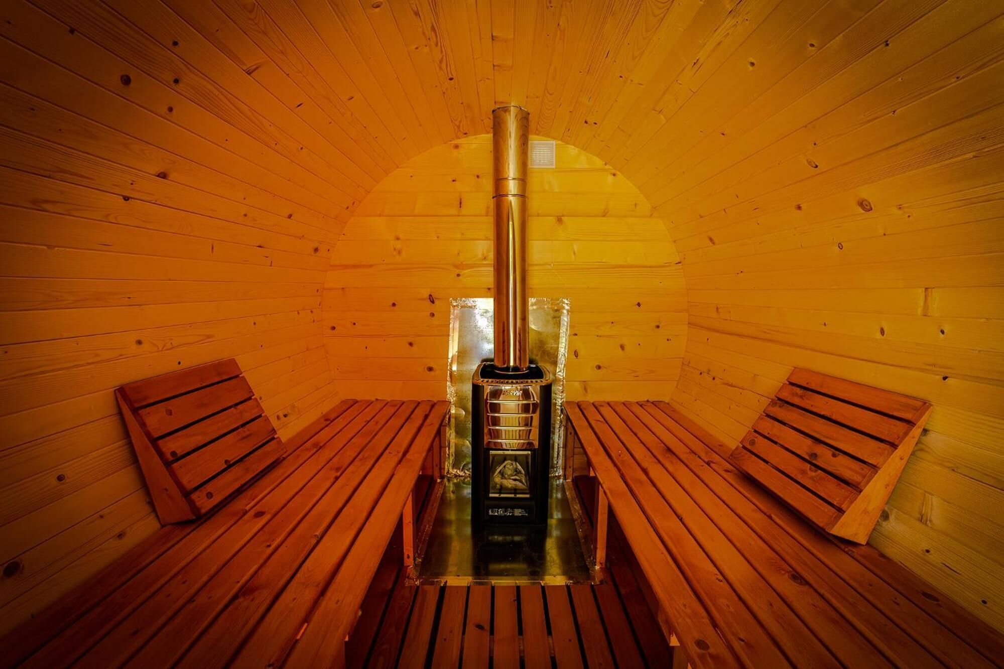 Una sala de sauna con bancos de madera y una unidad de sauna central.