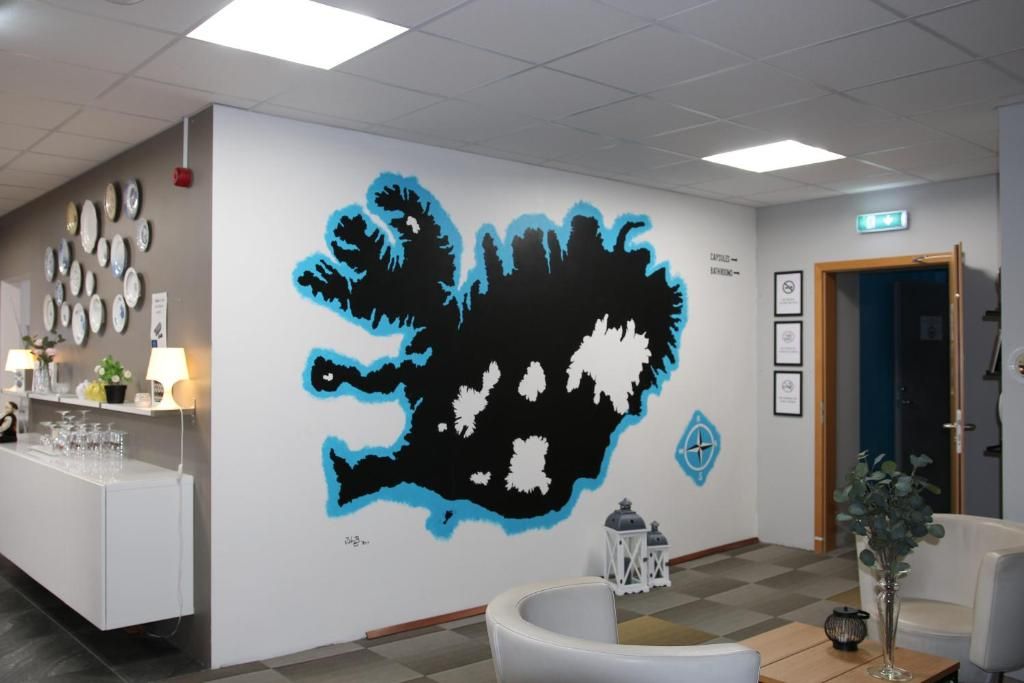 A reception area with a wall mural, a reception desk, chairs, and a small table with a vase.