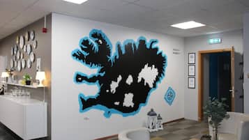 A reception area with a wall mural, a reception desk, chairs, and a small table with a vase.