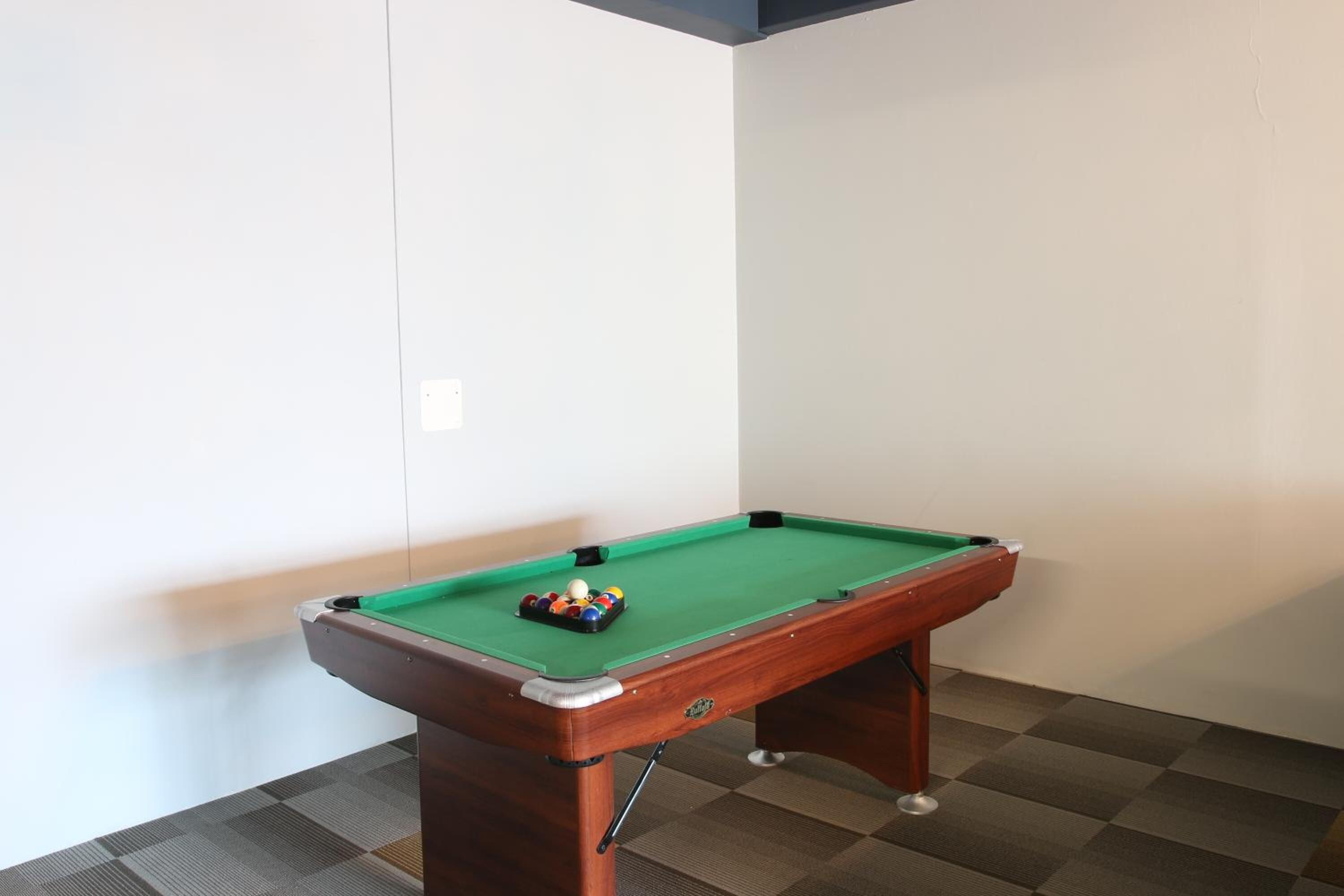 Een biljart met ballen in een hoekzaal met een geruit vloerkleed.