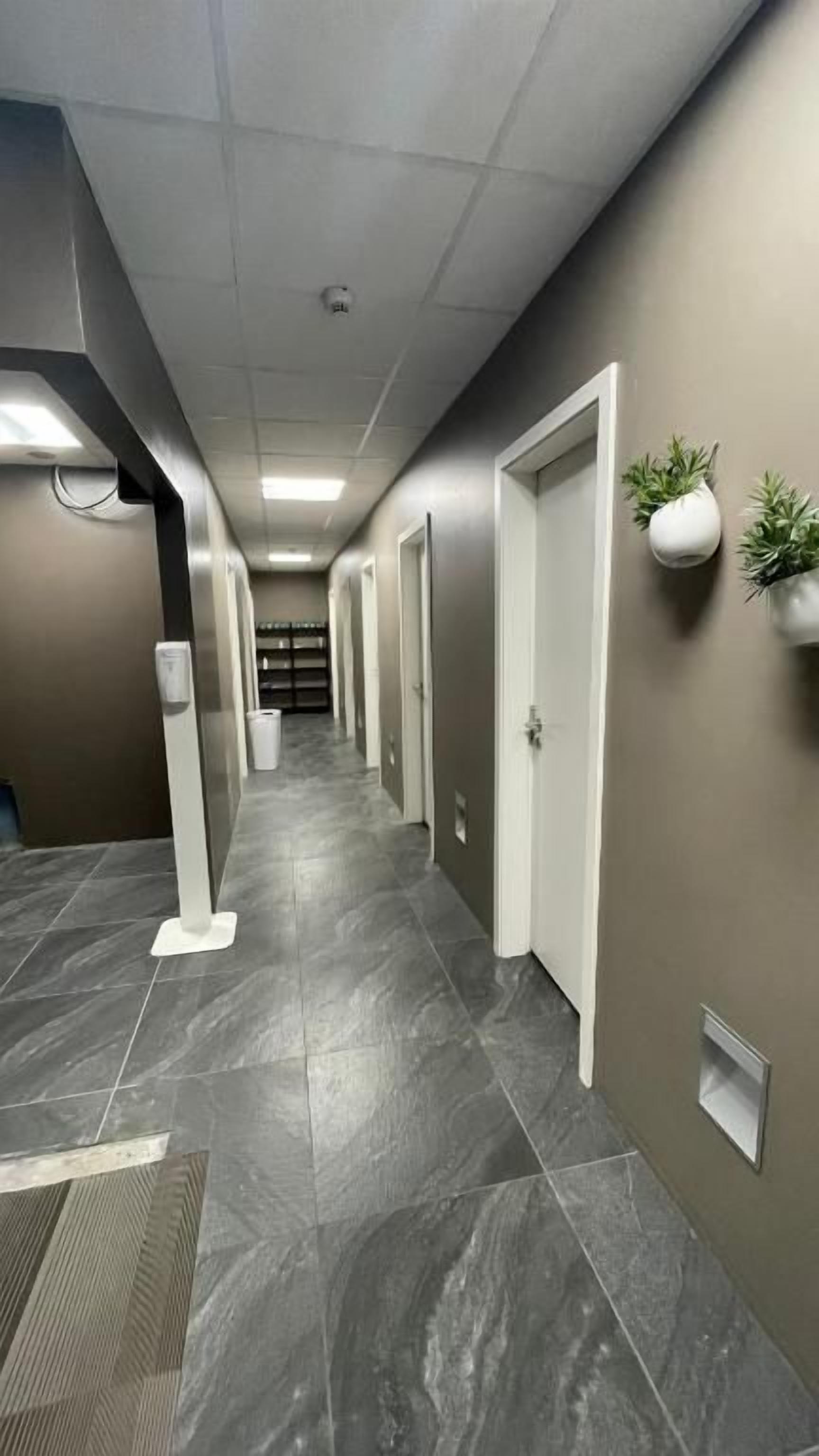 A hallway with a tiled floor, white doors, and wall-mounted planters.