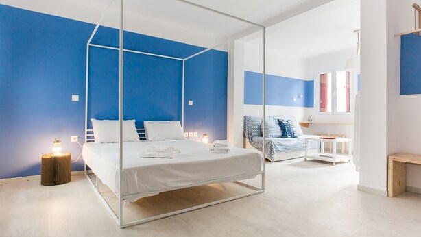 Un dormitorio moderno con cama con dosel, una mesita de noche con lámpara y otra mesita de noche más pequeña con lámpara.
