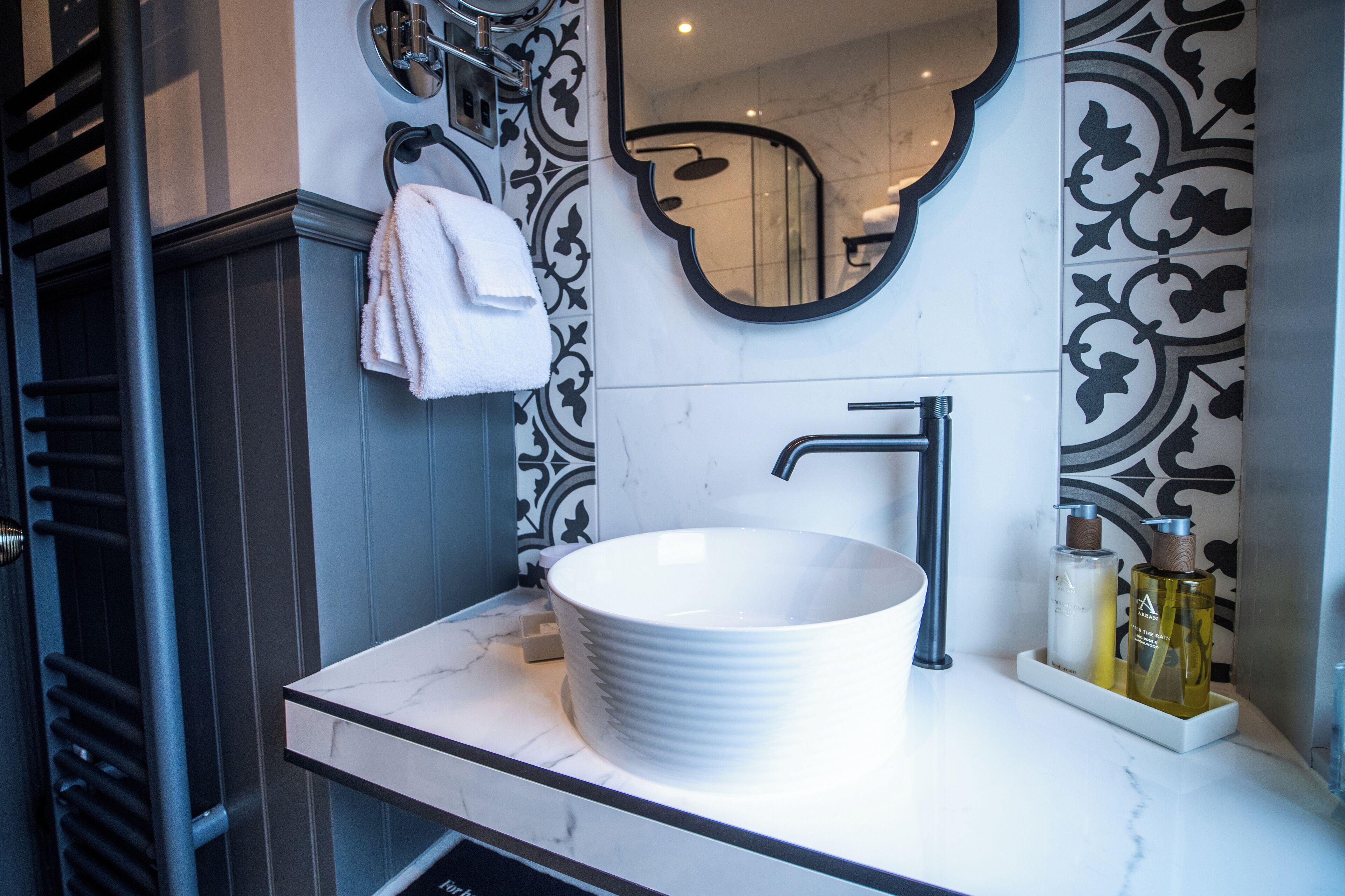 Un bany amb un lavabo de marbre blanc, un aixeta modern i rajoles decoratives a la paret.