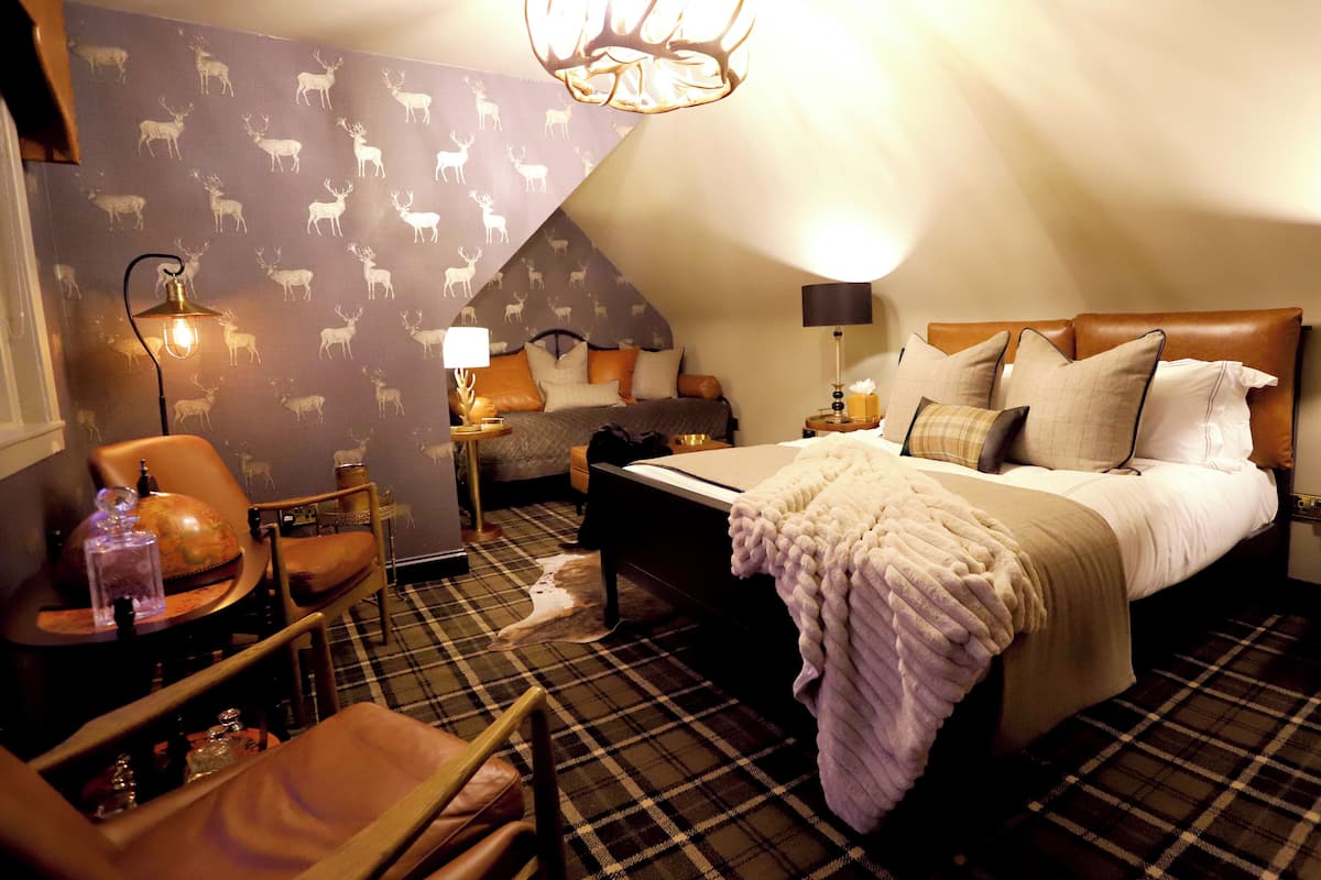 A cozy room with a bed, a chair, a lamp, and a wall with animal patterns.