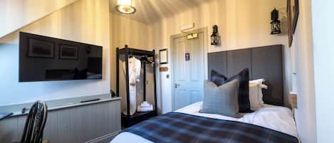 A hotel room with a bed, a desk, a chair, a wardrobe, and a mirror.