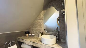 A bathroom with a marble vanity, a white sink, a large mirror, and a towel rack.