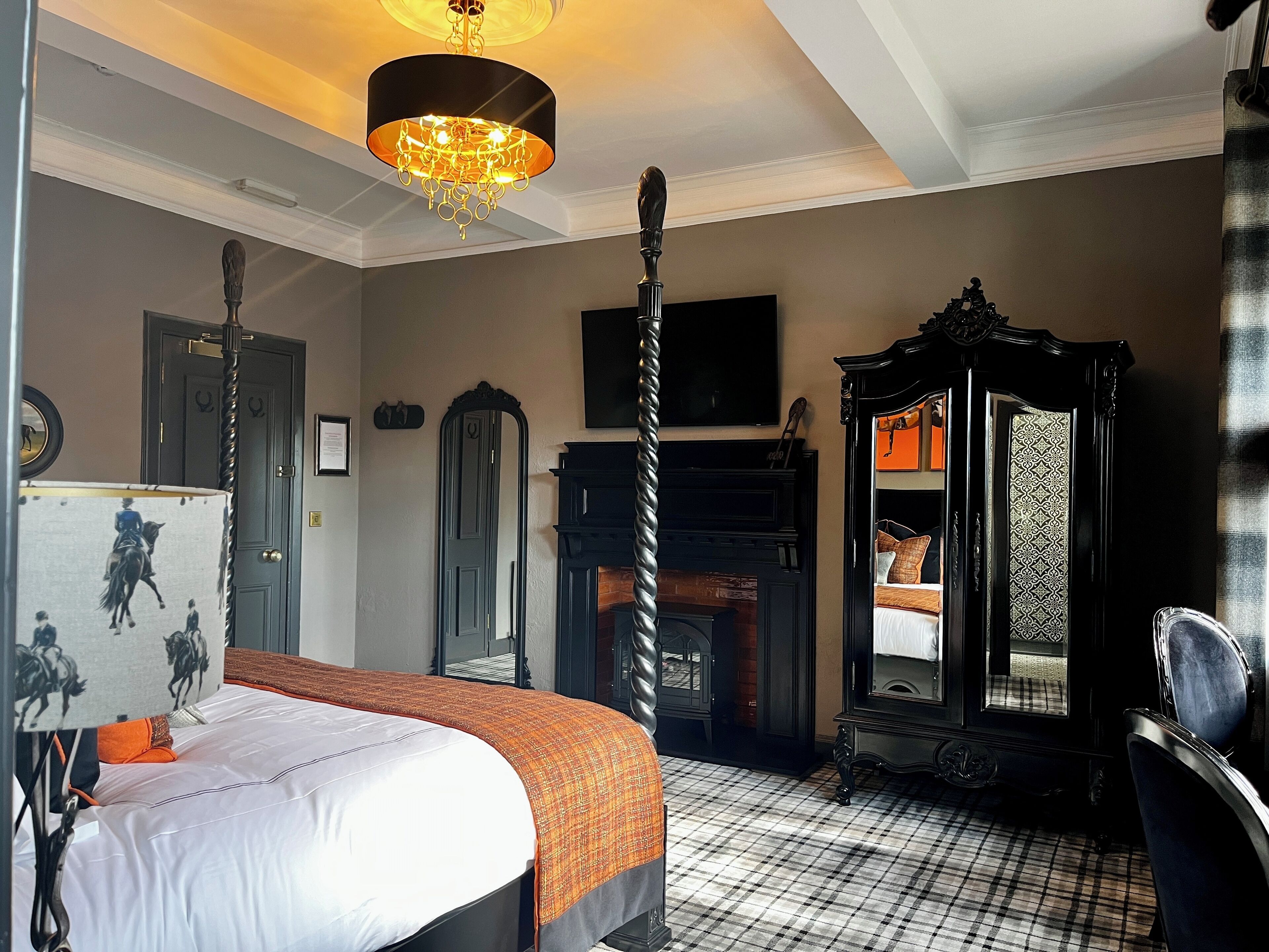 Ein Schlafzimmer mit Bett, Spiegel, Kamin und einer Chandelier.