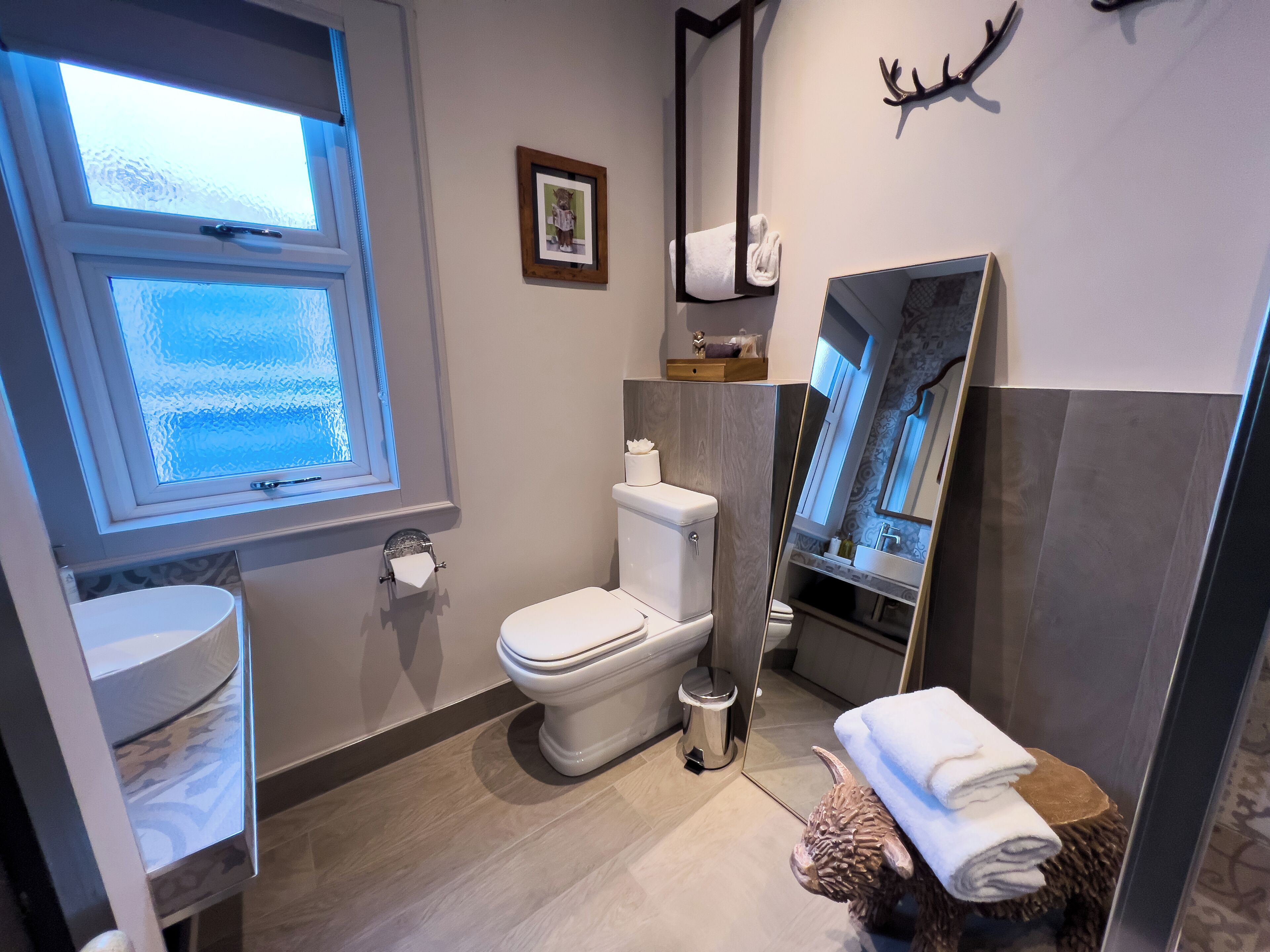 A modern bathroom with a toilet, sink, and large mirror.