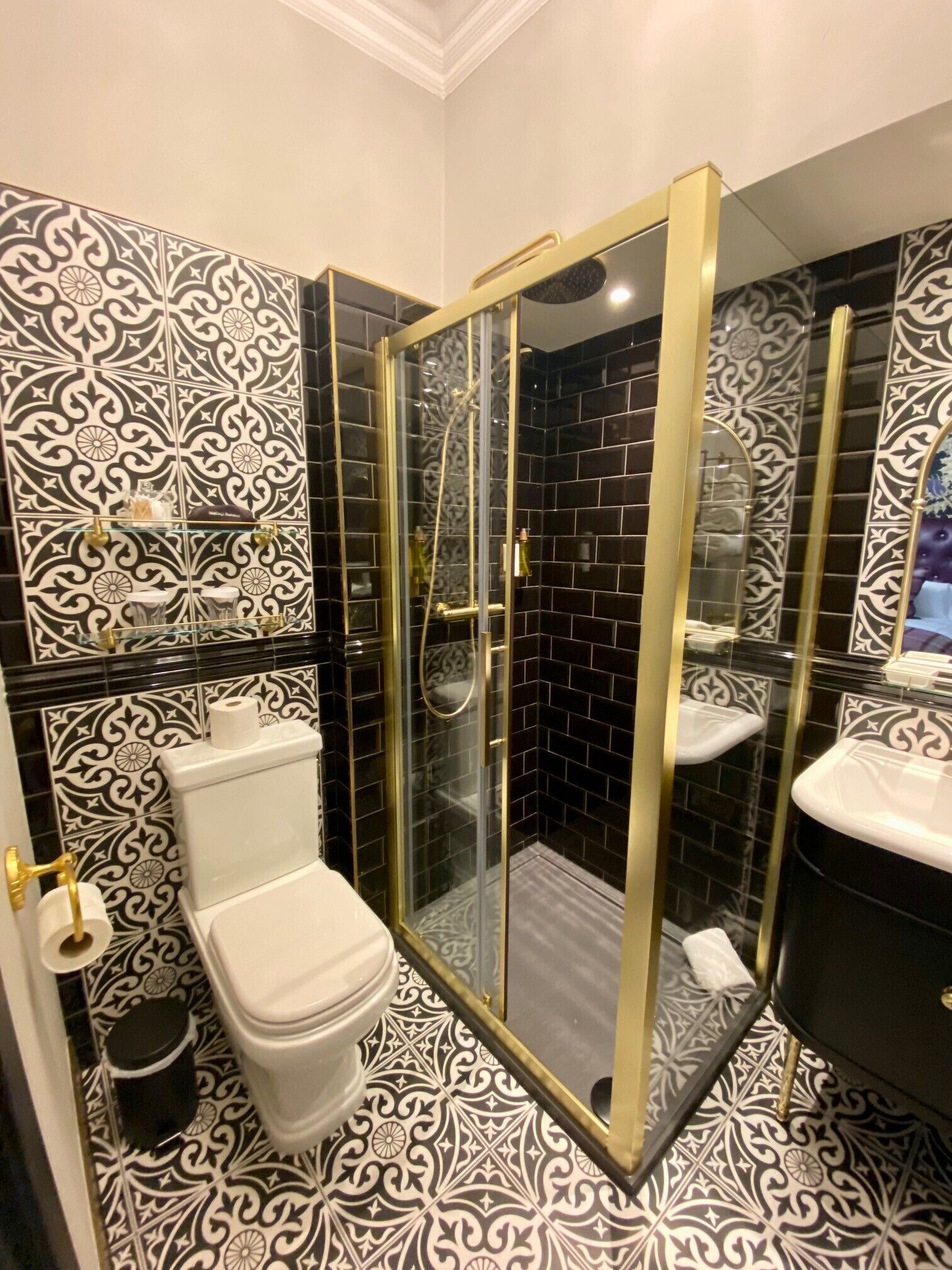 A bathroom with a glass-enclosed shower, a toilet, and a sink with a mirror.