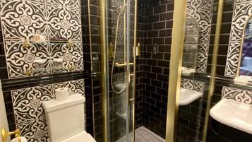 A bathroom with a glass-enclosed shower, a toilet, and a sink with a mirror.