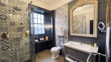 A bathroom with patterned tiles, a shower, a toilet, a sink, and a mirror.