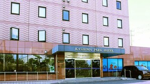 Un hotel con fachada moderna, entrada destacada y zona de estacionamiento visible.