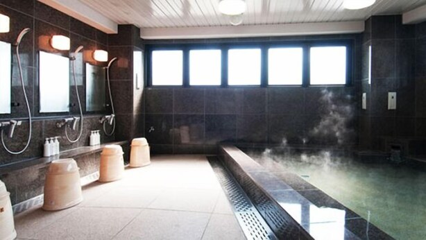 Un baño moderno con ducha de vapor, varios lavamanos y ventanas amplias.