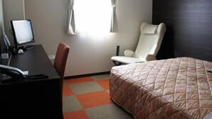 Una habitación de hotel con cama, escritorio con ordenador, silla y ventana con cortinas.