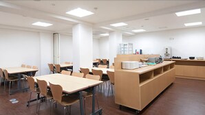 Un aula con mesas y sillas, un escritorio de profesor y una pizarra.