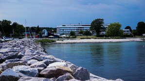 A waterfront hotel with a rocky shoreline, a building with multiple floors, and a clear sky. - Hotel Marina (Vedbaek)