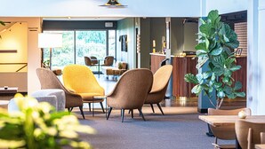 A modern dining area with contemporary chairs, a large potted plant, and a view of the outdoors. - Hotel Marina (Vedbaek)