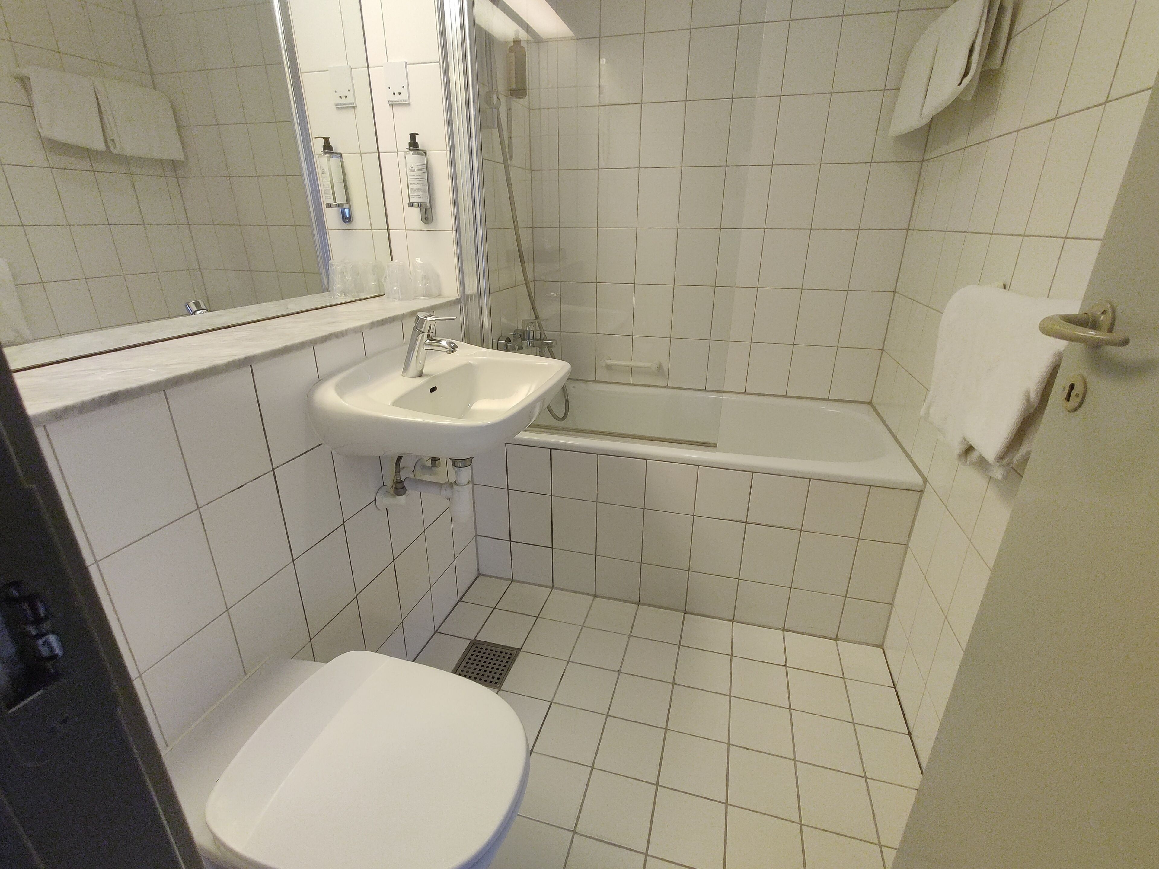 A bathroom with a sink, mirror, toilet, and bathtub.
